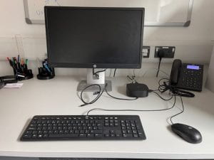 A keyboard, mouse, monitor and docking station on a desk.
