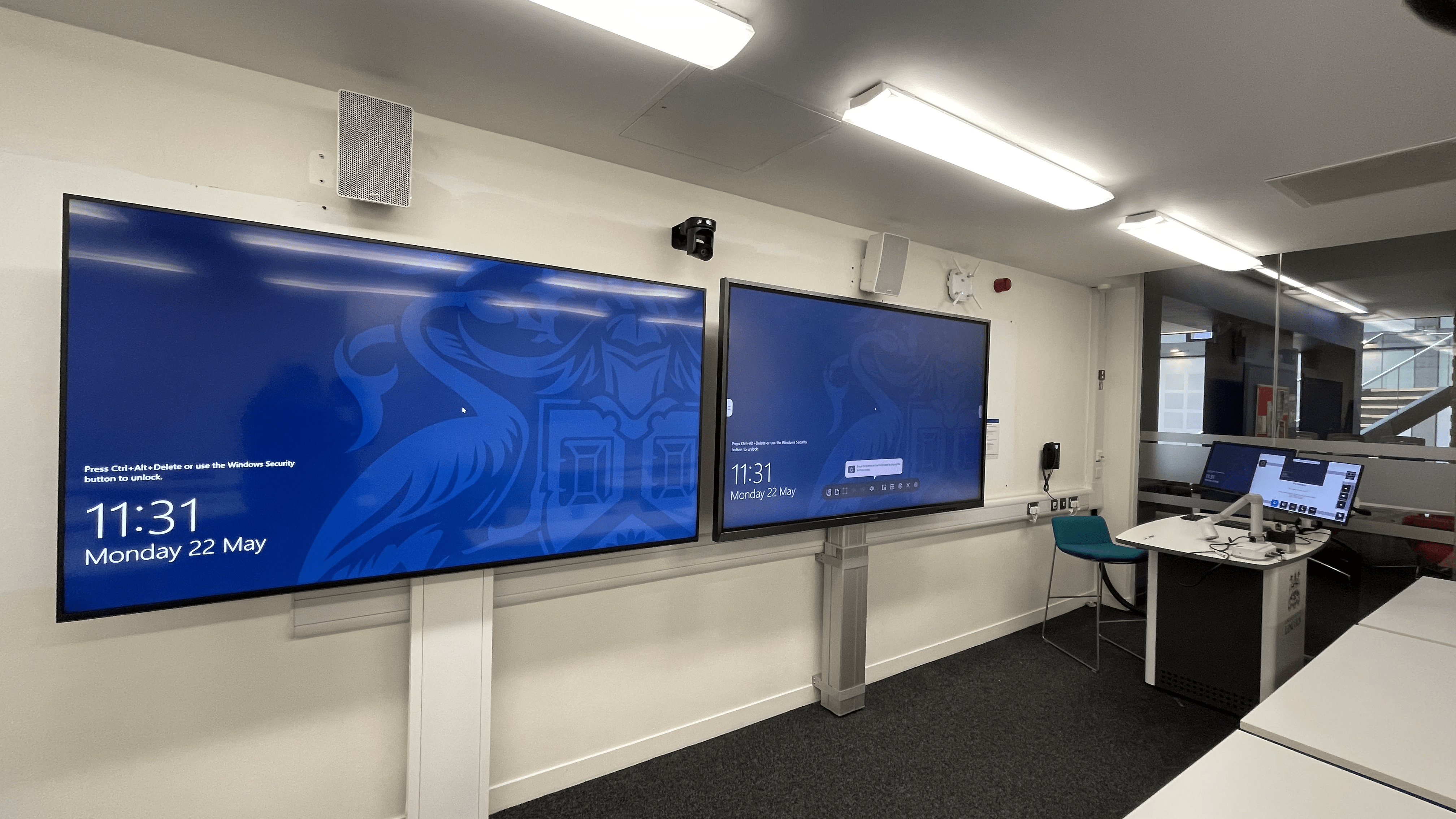 Two widescreen displays in a seminar room.